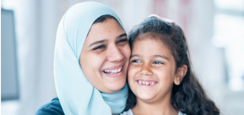 A mother and a daughter sat close together smiling.
